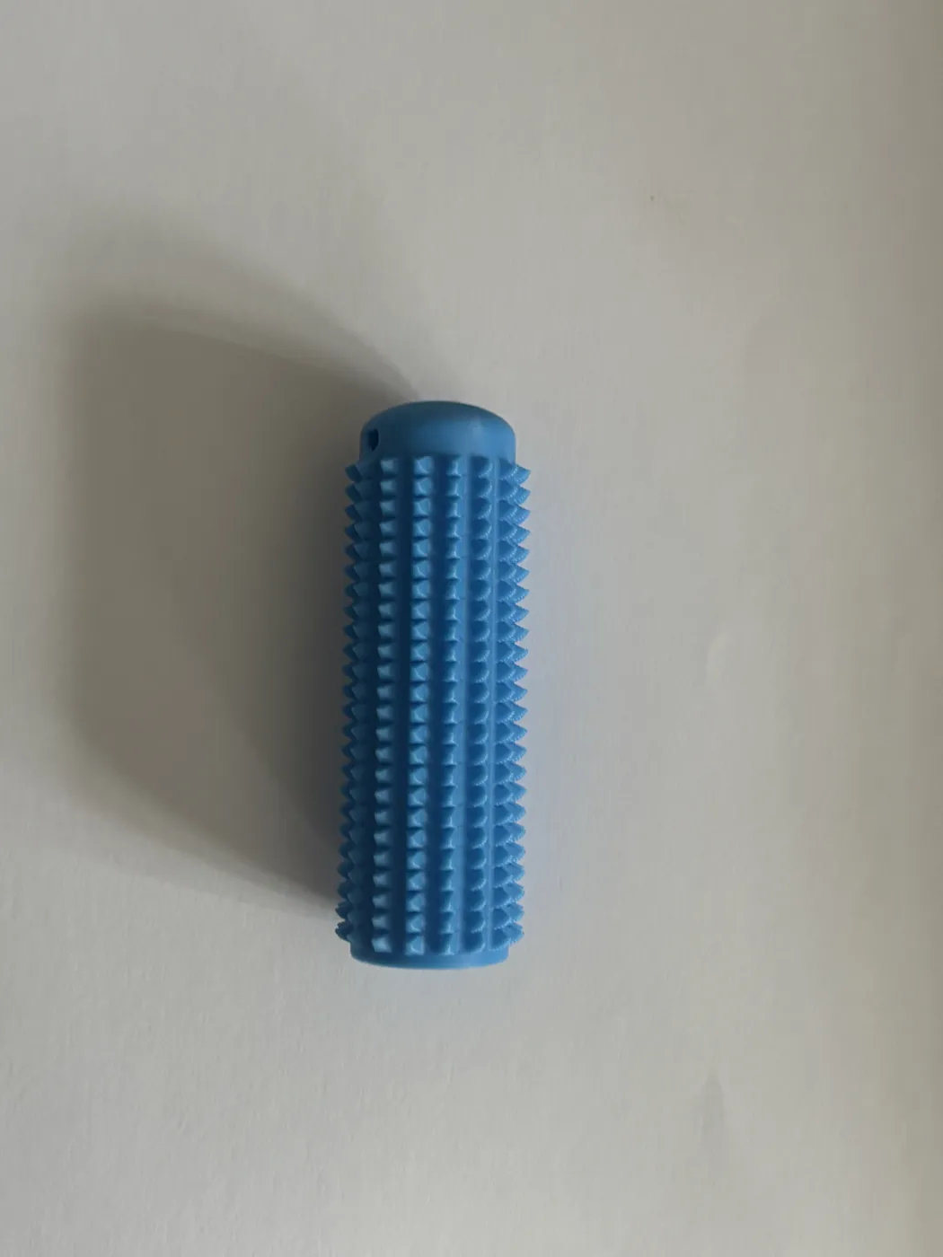 A blue cylindrical 3D print covered in small spikes, standing upright