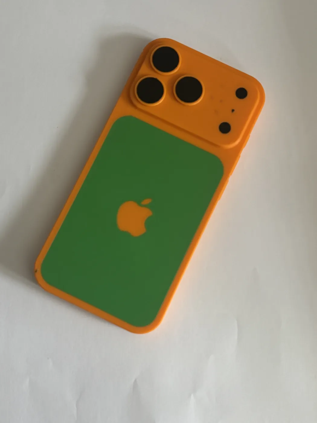 A 3D-printed model shaped like the back of a phone, in orange with a green panel