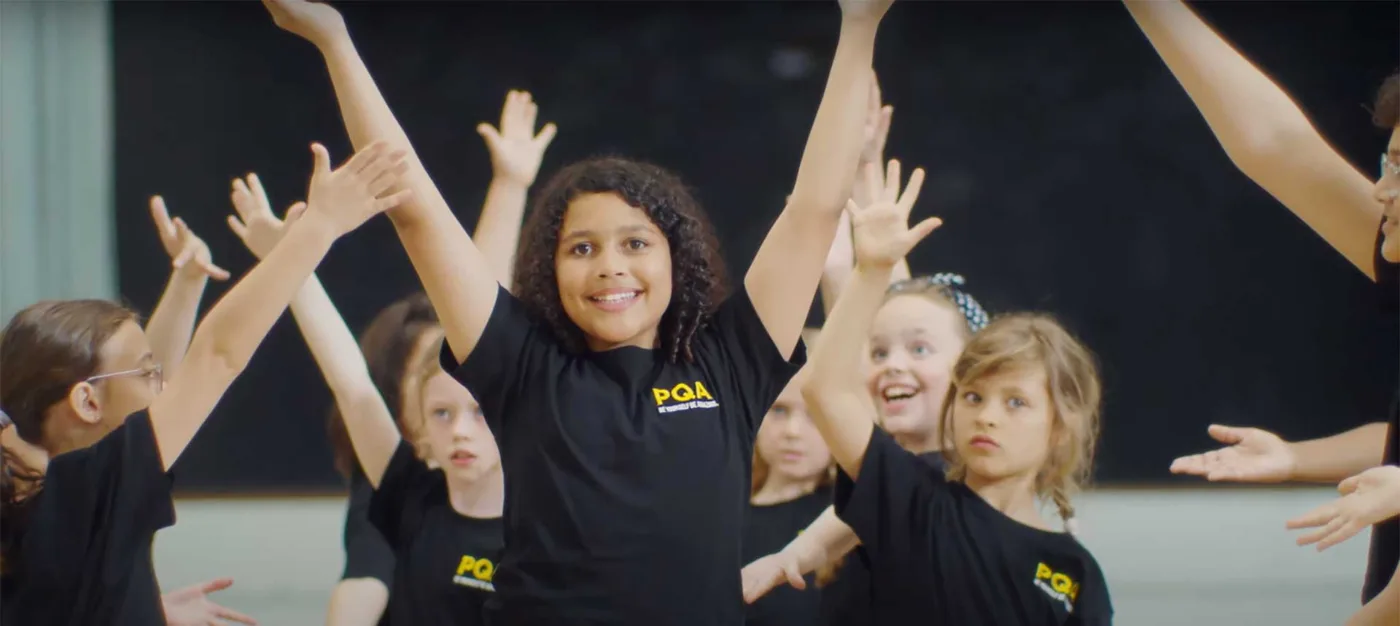 Children in PQA T-shirts during a performing arts session.